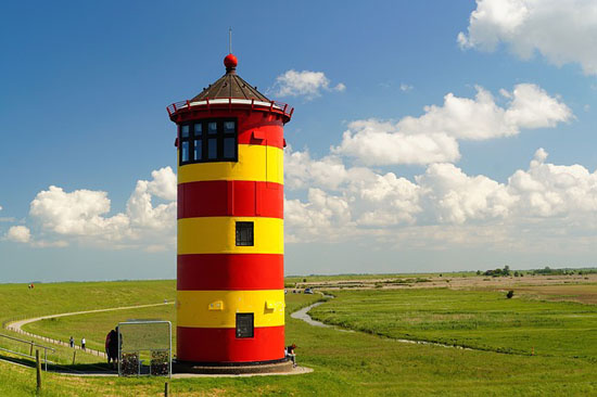 Der gelbrot geringelte Pilsumer Leuchtturm grüßt die Radler auf dem Nordsee-Radweg. (Foto: djd)